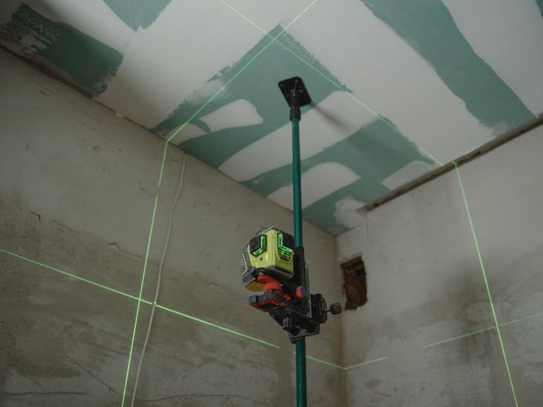Linienlaser wirft grüne Linien an Wand und Decke und markiert die Lage der künftigen Trennwand
